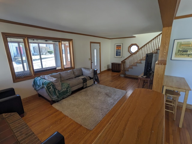 living area with stairway, baseboards, wood finished floors, and ornamental molding