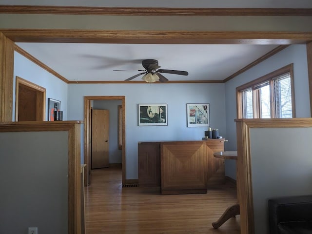 interior space with a ceiling fan, crown molding, wood finished floors, and baseboards