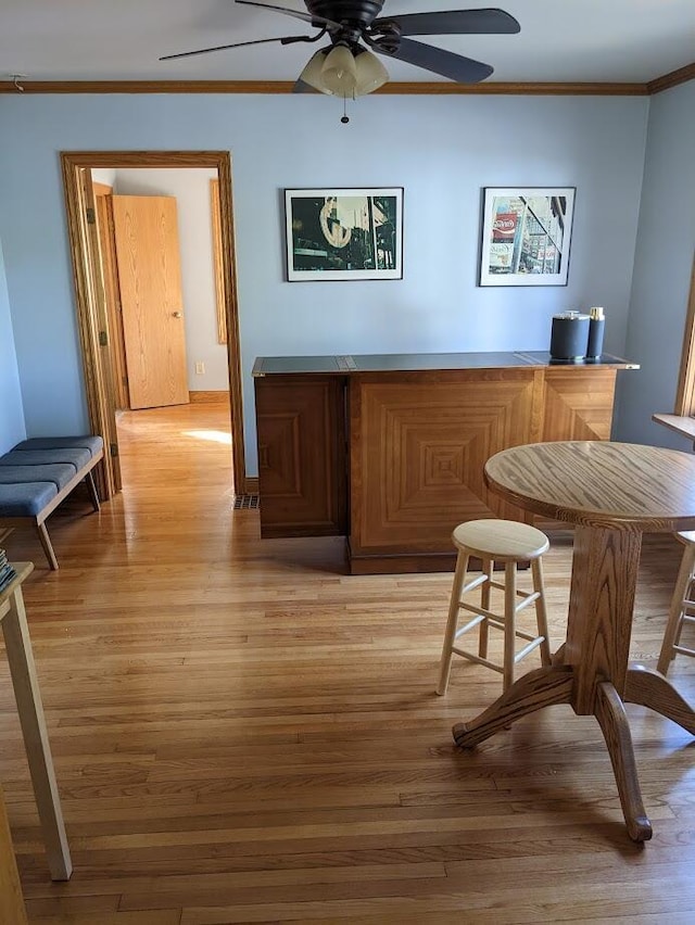 bar featuring crown molding, light wood-type flooring, and ceiling fan