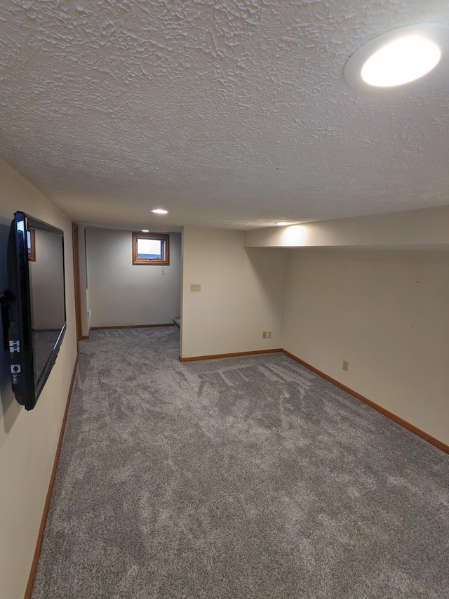 basement featuring carpet flooring, baseboards, and a textured ceiling