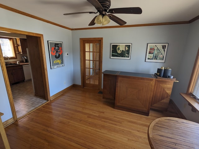 office area with light wood-style flooring, ornamental molding, baseboards, and a sink