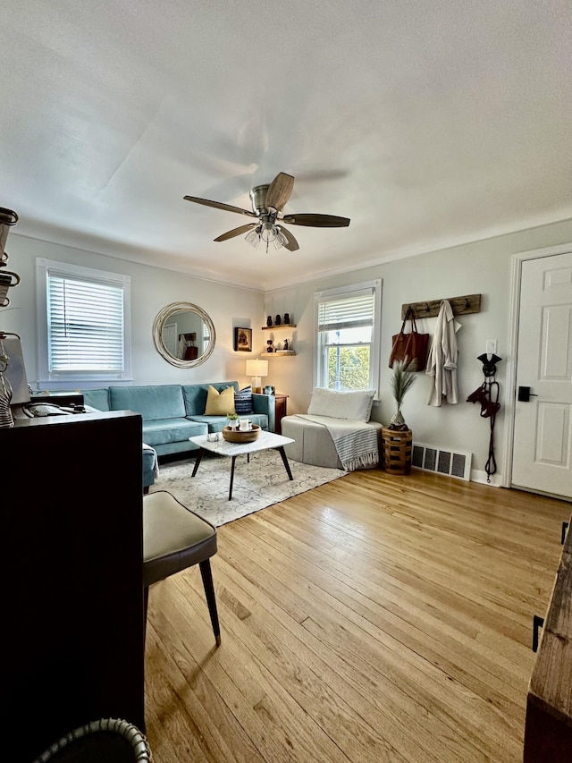 living room featuring hardwood / wood-style floors, a ceiling fan, and visible vents