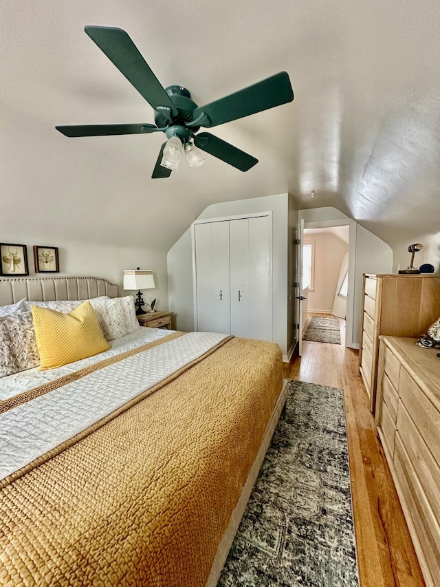 bedroom featuring a closet, light wood-style floors, baseboards, ceiling fan, and vaulted ceiling