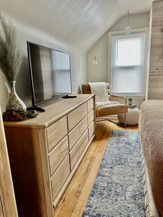 bedroom with lofted ceiling and light wood finished floors