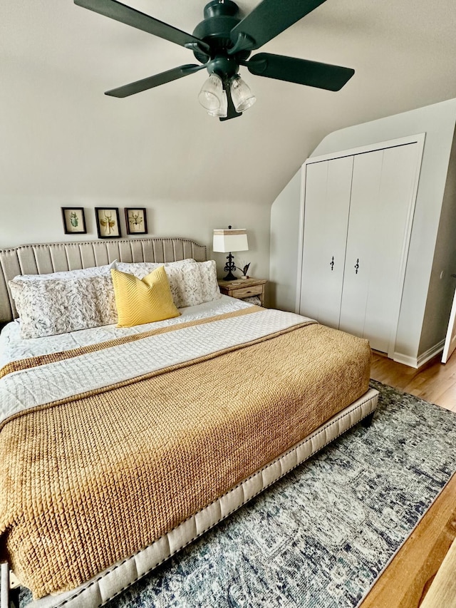 bedroom with a closet, a ceiling fan, lofted ceiling, and wood finished floors