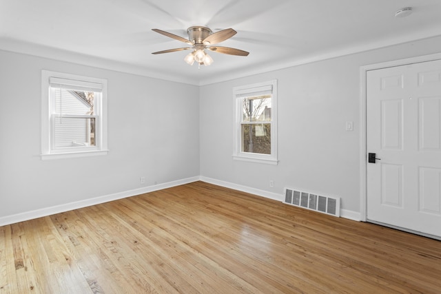 empty room featuring light wood-style flooring, a healthy amount of sunlight, visible vents, and baseboards