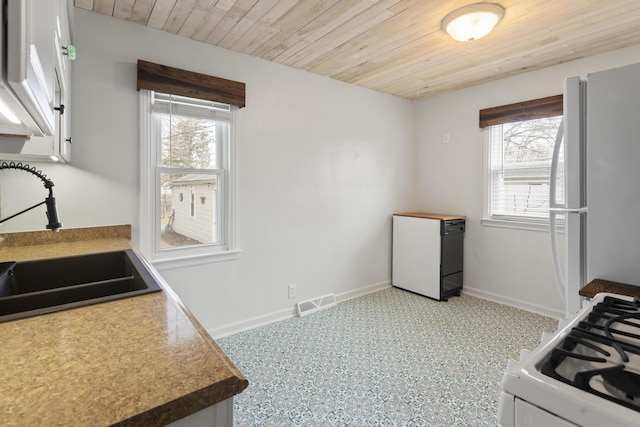 kitchen featuring plenty of natural light, white appliances, wood ceiling, and a sink