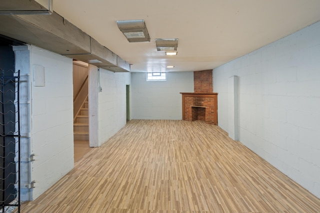 basement featuring a brick fireplace, stairs, and wood finished floors