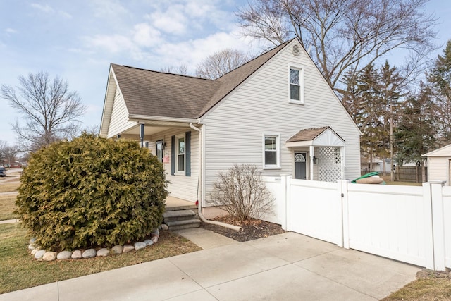 view of front of house with fence, roof with shingles, and a gate