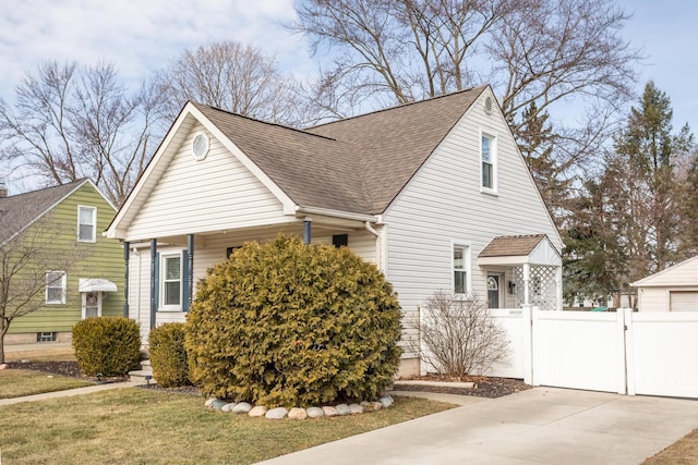 view of property exterior featuring fence, roof with shingles, a lawn, driveway, and a gate