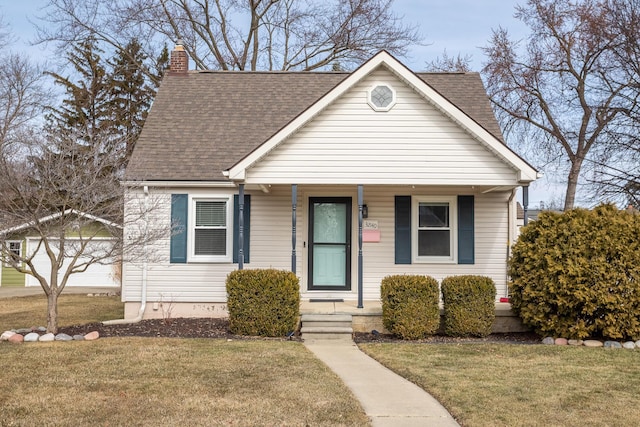 bungalow with a porch, a chimney, a front lawn, and roof with shingles