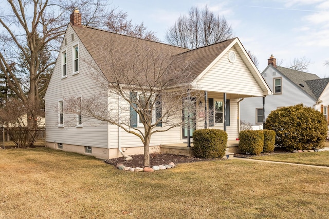 view of front facade with a front lawn, covered porch, roof with shingles, and a chimney