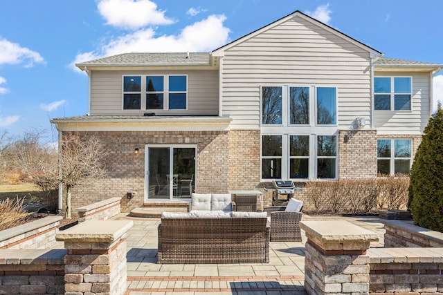 back of house featuring an outdoor living space, a patio, and brick siding