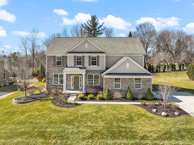 traditional home featuring a front yard, brick siding, and roof with shingles