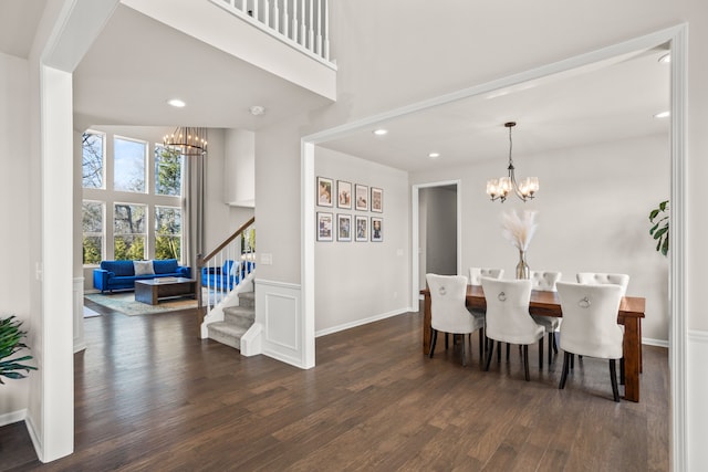 dining space featuring stairs, a notable chandelier, wood finished floors, and a towering ceiling