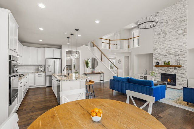 dining room with recessed lighting, a stone fireplace, dark wood-style floors, and stairs