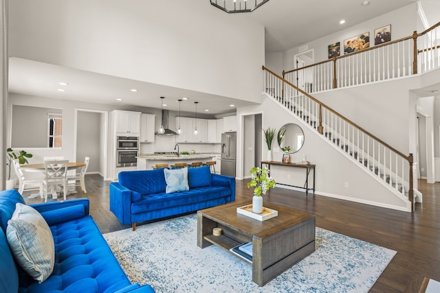 living room with baseboards, a high ceiling, wood finished floors, and stairs