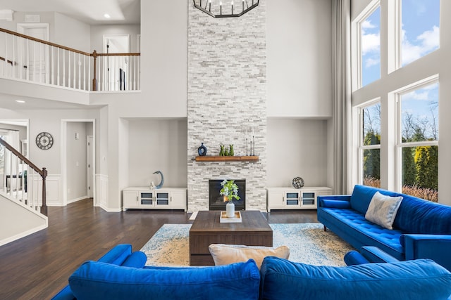 living area with a wealth of natural light, stairway, wood finished floors, and a fireplace