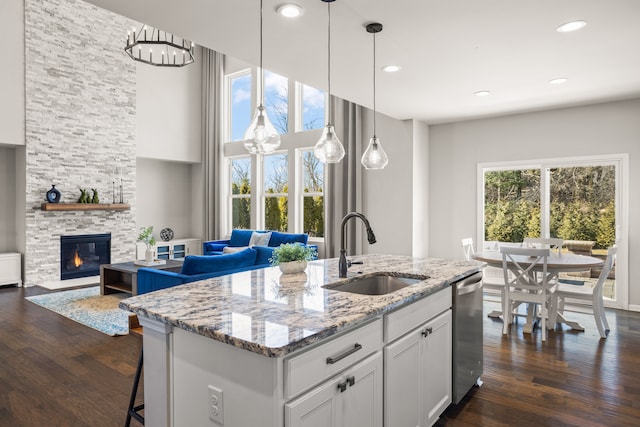 kitchen featuring dishwasher, open floor plan, dark wood-style flooring, and a sink