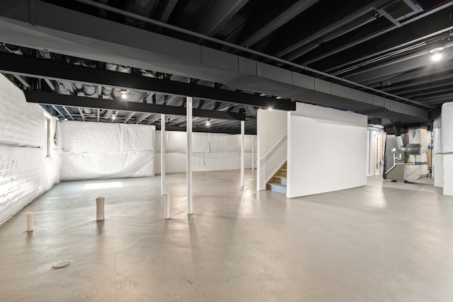 unfinished basement featuring stairway and heating unit