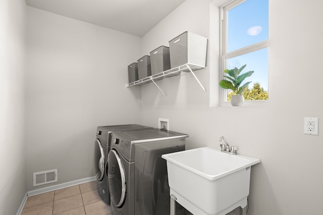 clothes washing area with visible vents, laundry area, light tile patterned flooring, a sink, and washer and dryer