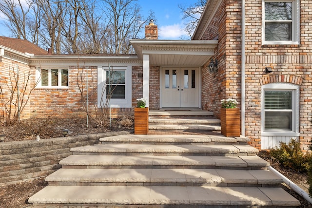 entrance to property with brick siding and a chimney