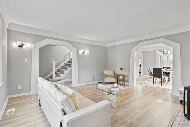 living room with visible vents, arched walkways, light wood-style floors, and stairs