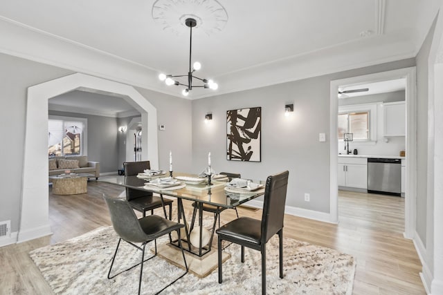 dining area featuring visible vents, baseboards, an inviting chandelier, arched walkways, and light wood-type flooring