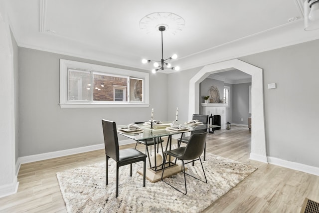 dining room with baseboards, arched walkways, light wood finished floors, and a chandelier