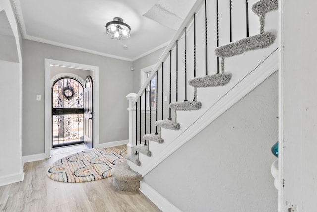 entryway with ornamental molding, stairs, baseboards, and wood finished floors