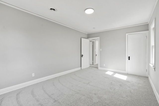 carpeted spare room with visible vents, baseboards, and ornamental molding