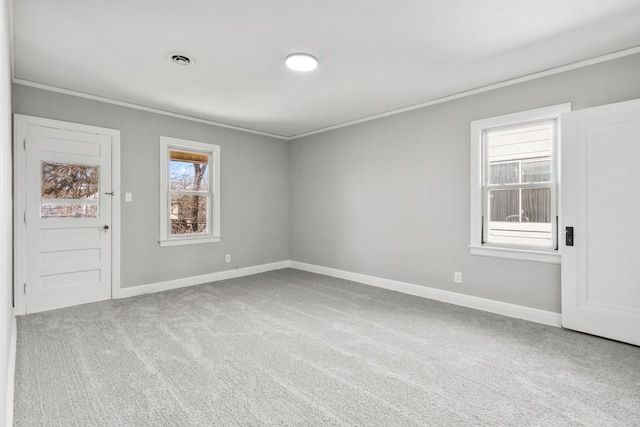 carpeted empty room featuring visible vents, baseboards, and ornamental molding