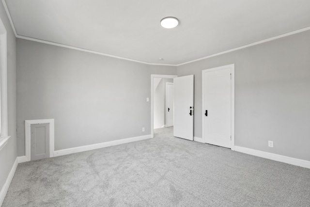 spare room with crown molding, carpet flooring, and baseboards