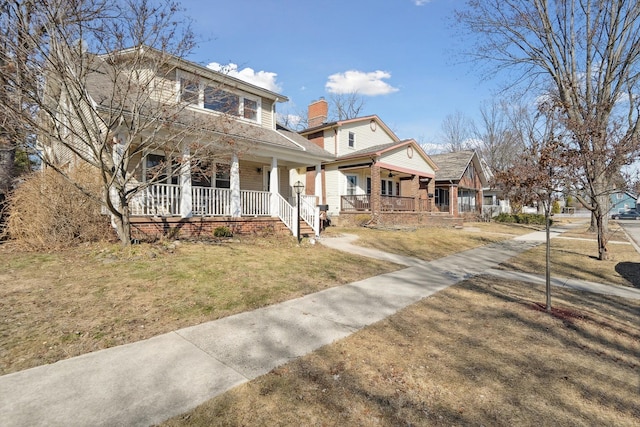 view of front of home featuring a front yard, covered porch, and a chimney