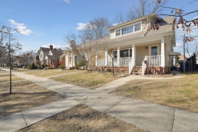 bungalow-style house with a porch, a front lawn, and roof with shingles