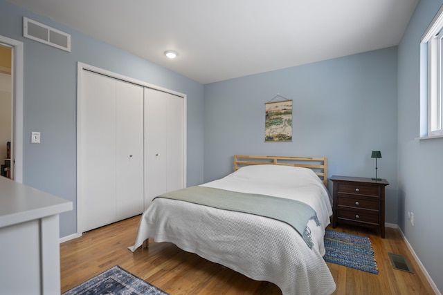 bedroom featuring light wood-style floors, visible vents, a closet, and baseboards