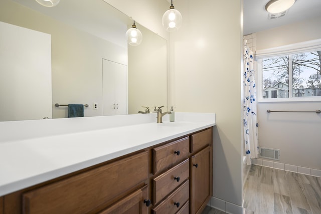 bathroom with visible vents, wood finished floors, a shower with shower curtain, baseboards, and vanity