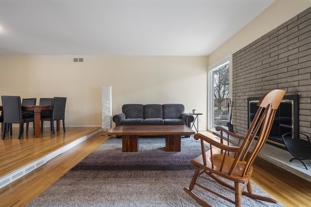 living room with visible vents, a fireplace, baseboards, and wood finished floors