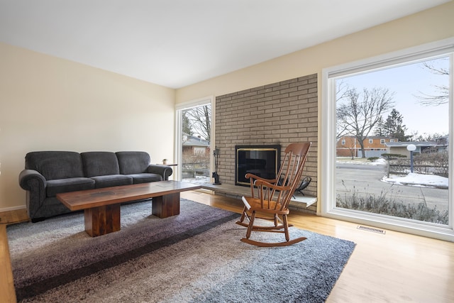 living area featuring visible vents, a brick fireplace, and wood finished floors