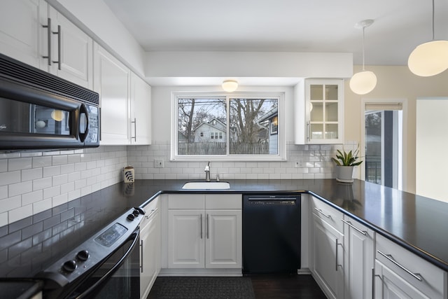 kitchen featuring black appliances, dark countertops, backsplash, and a sink