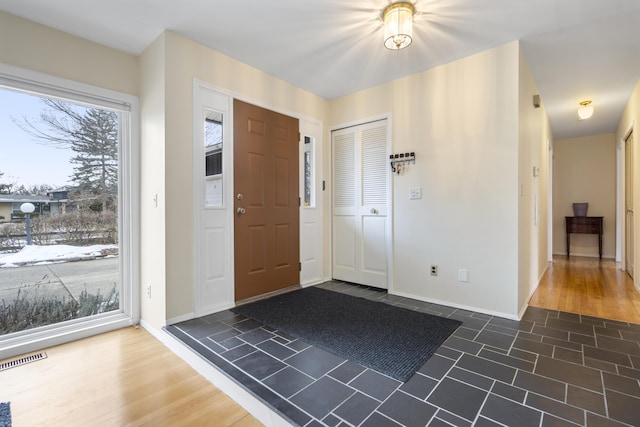 foyer entrance with visible vents, baseboards, and dark wood-type flooring