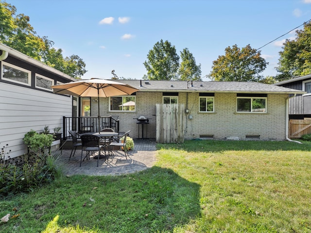 rear view of house featuring a yard, fence, brick siding, and a patio area