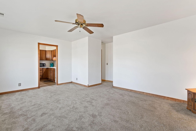 empty room with visible vents, light colored carpet, baseboards, and ceiling fan