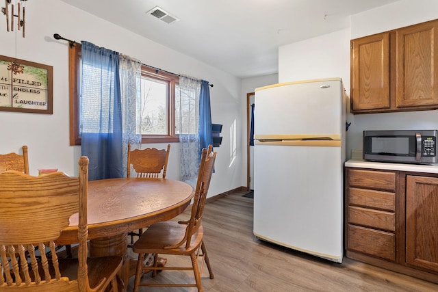 dining space featuring baseboards, visible vents, and light wood finished floors