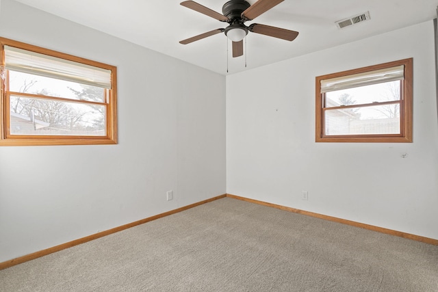 unfurnished room with a healthy amount of sunlight, visible vents, carpet floors, and baseboards