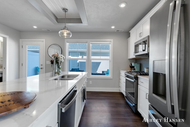 kitchen with a tray ceiling, decorative backsplash, appliances with stainless steel finishes, dark wood-style floors, and a sink