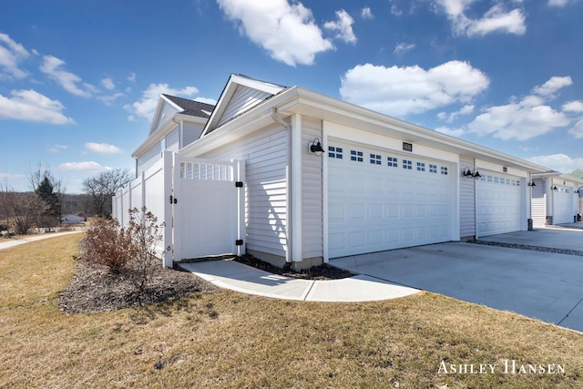 view of side of home with a yard, driveway, a garage, and a gate