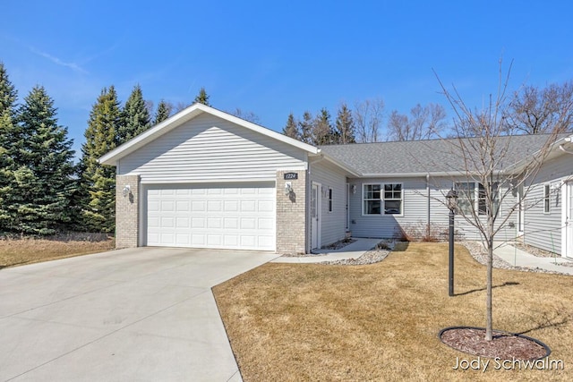 single story home with a front yard, an attached garage, brick siding, and driveway