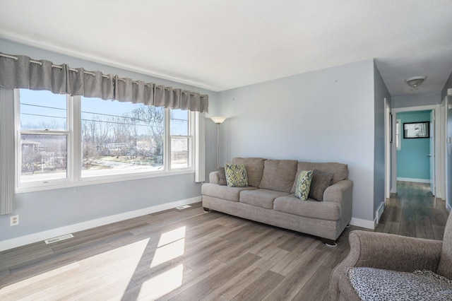 living area with visible vents, baseboards, and wood finished floors