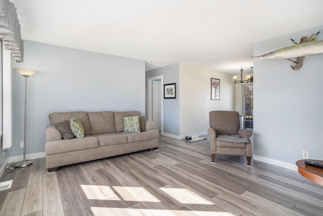 living area with an inviting chandelier, baseboards, and light wood finished floors